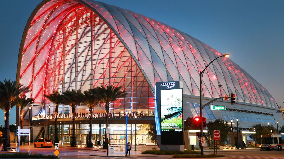 The Anaheim Regional Transportation Intermodal Center, a long vaulted ETFE arch lit red against a blue evening sky