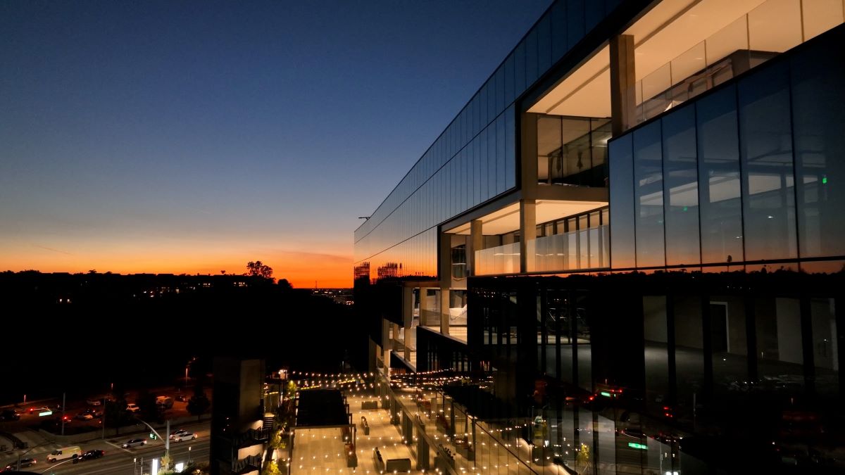 A glazed facade catching the last of the sunset above a lit terrace